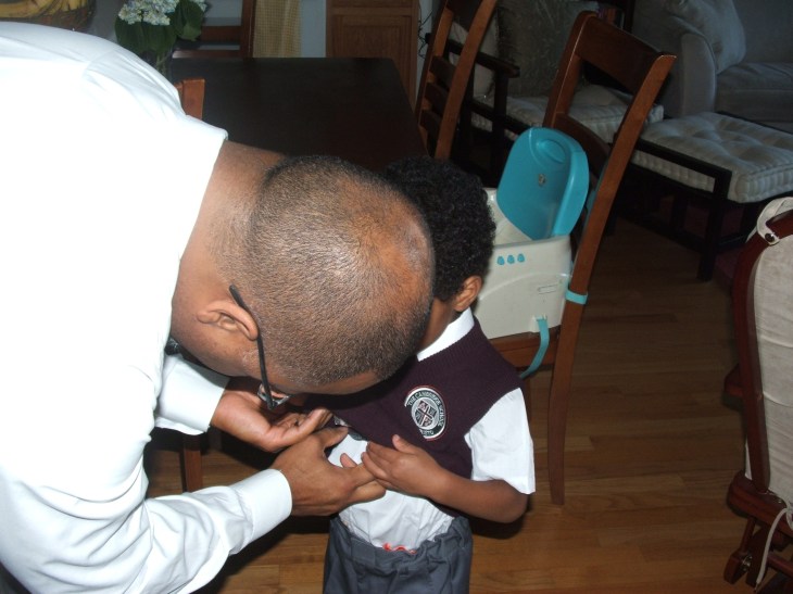 Pulling the tie down the middle, over the stomach, and lining it up behind the vest